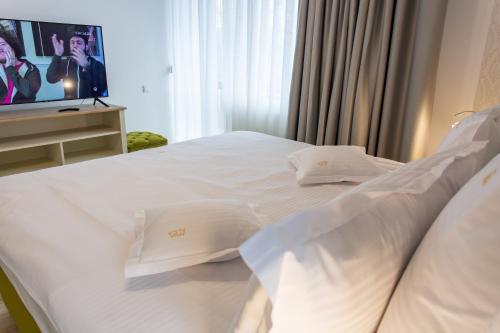 a white bed with white pillows and a tv at Pension Carmen`s Mansion A in Sinaia