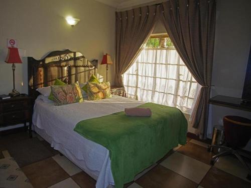 sypialnia z łóżkiem z zielonym kocem w obiekcie Maroela Guesthouse Brits w mieście Brits