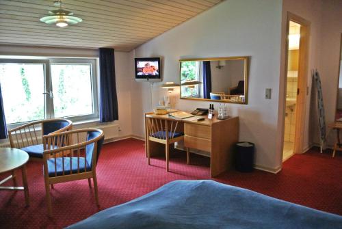 a hotel room with a desk and a mirror at Agerskov Kro & Hotel in Agerskov