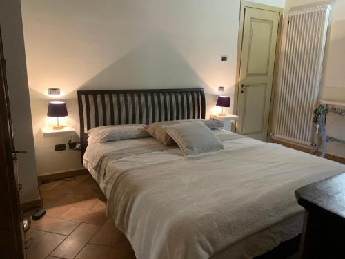 a bedroom with a large white bed with two lamps at Casa del Borgo in Cantiano