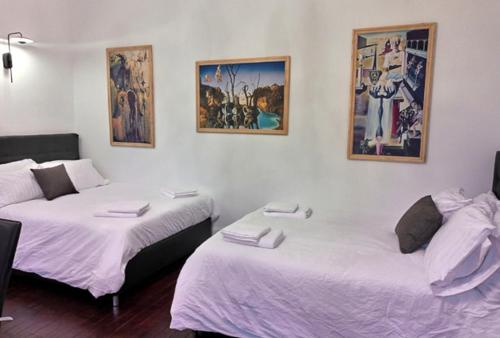 two beds in a room with pictures on the wall at Les Appartements Fénelon in Le Cateau