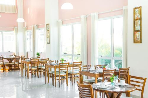 Oceania Park Hotel Spa & Convention في فلوريانوبوليس: غرفة طعام مع طاولات وكراسي ونوافذ