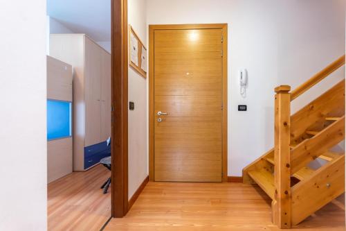 a hallway with a wooden door and a staircase at Casa NeveXenne & La Casa di Blek in Alleghe