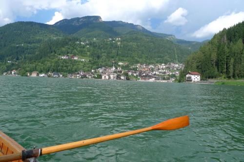 a person paddling a boat on a lake with a town at Casa NeveXenne & La Casa di Blek in Alleghe