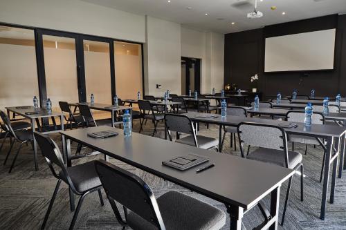 a conference room with tables and chairs and a screen at The Catalyst Apartment Hotel by NEWMARK in Johannesburg