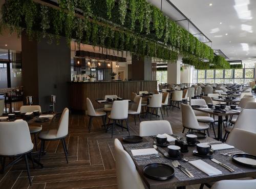 a dining room with tables and chairs and plants at The Catalyst Apartment Hotel by NEWMARK in Johannesburg
