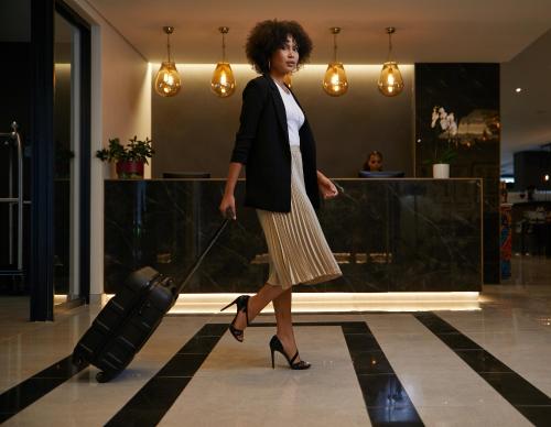a woman pulling a suitcase in a lobby at The Catalyst Apartment Hotel by NEWMARK in Johannesburg