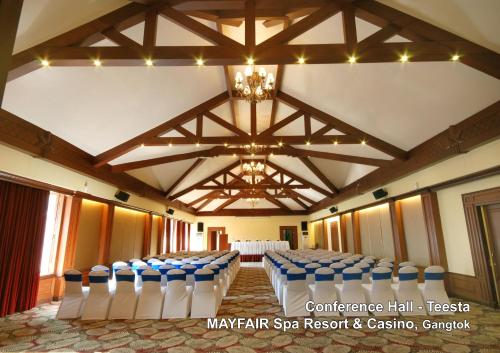 a banquet hall with blue and white chairs and a chandelier at Mayfair Spa Resort & Casino in Gangtok