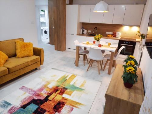een keuken en woonkamer met een tafel en een bank bij Apartament Amber Comfort z prywatnym miejscem parkingowym in Kołobrzeg