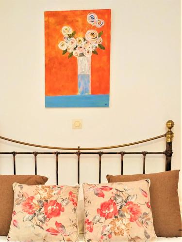 a bedroom with a bed with a painting on the wall at My Little Suites in Ermoupoli