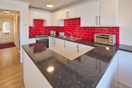 uma cozinha com armários brancos e azulejos vermelhos em Host & Stay - Rock Cottage em Whitby