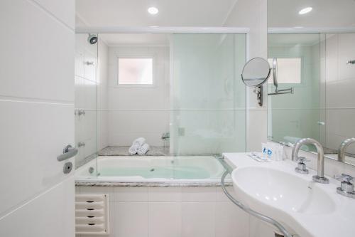 a bathroom with a tub and a sink and a mirror at Oceania Park Hotel Spa & Convention by RB Hotelaria in Florianópolis
