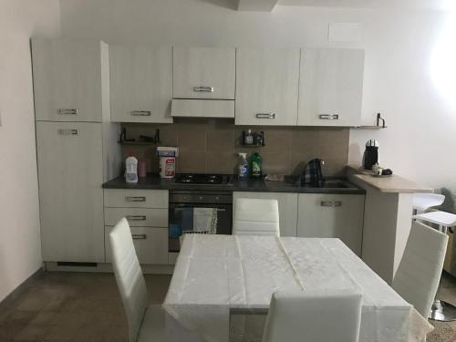 eine Küche mit weißen Schränken sowie einem Tisch und Stühlen in der Unterkunft I colori della Tuscia in Caprarola