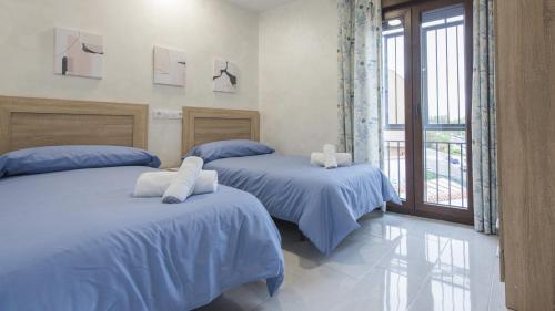 Un dormitorio con dos camas con sábanas azules y una ventana. en La casita del caracol by Toledo AP, en Toledo