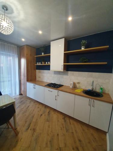 uma cozinha com armários brancos e piso em madeira em ЖК Яровиця em Lutsʼk