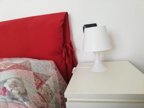 - un lit avec un oreiller rouge et une lampe sur une table de nuit dans l'établissement La Piazzetta, à Stresa