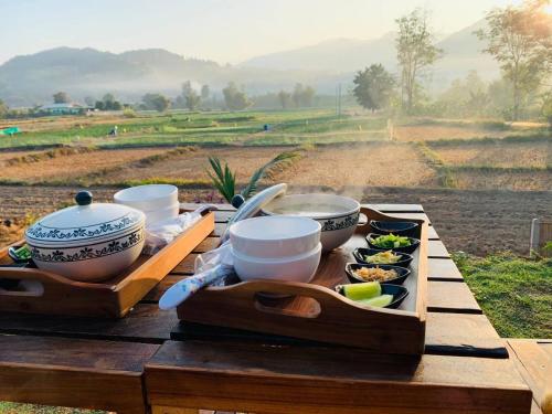 a table with bowls and plates of food on it at เฮือนป้อหลวง in Ban Fang