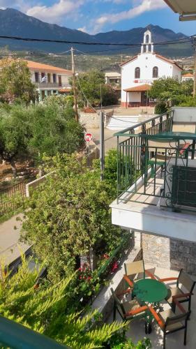 a balcony with tables and chairs and a building at Vasiliki Apartments in Stoupa