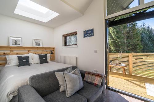 a bedroom with a bed and a couch and a sliding glass door at The Trossachs Collection in Kepculloch