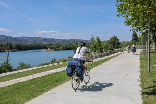 a man riding a bike down a sidewalk next to a lake at Kyriad Direct - Bourg les Valence in Bourg-lès-Valence