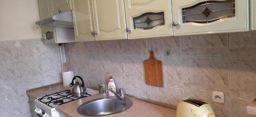 a kitchen with a sink and a stove and cabinets at Mieszkanie w Giżycku in Giżycko