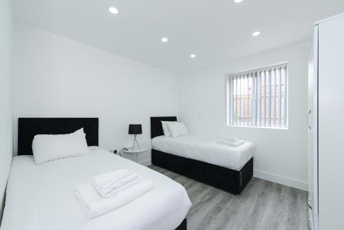 a white room with two beds and a window at Adbolton House Apartments - Sleek, Stylish, Brand New & Low Carbon in Nottingham