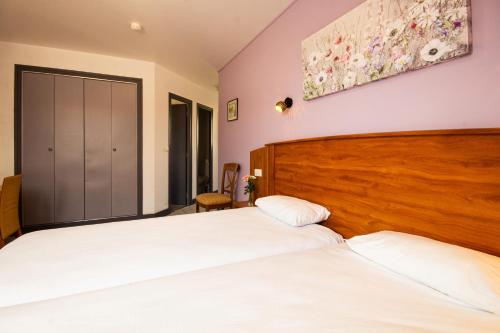 two beds in a room with two white beds at CIT'HOTEL Le Commerce in Saujon