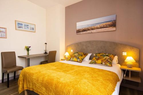 a bedroom with a large bed with a yellow blanket at CIT'HOTEL Le Commerce in Saujon