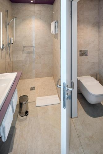 a bathroom with a shower and a toilet and a sink at Hotel am Remspark in Schwäbisch Gmünd