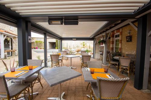 an outdoor patio with tables and chairs and windows at CIT'HOTEL Le Commerce in Saujon