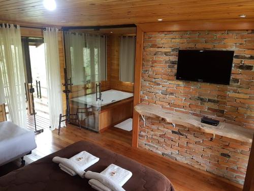 a living room with a brick wall and a tv at Pousada Cajuvá in Urubici