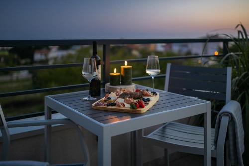 a table with a plate of food and two glasses of wine at Belvedere Holidays in Novigrad Istria