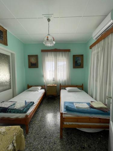 two beds in a room with green walls and a window at Odysseus in Vrontados