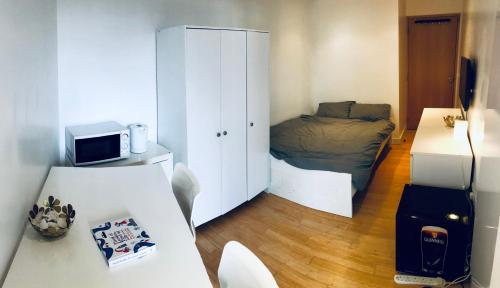 a small room with a bedroom with a bed and a desk at Double Room with Private Balcony in London