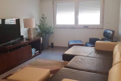a living room with a couch and a tv at Sal Guest House in Costa da Caparica