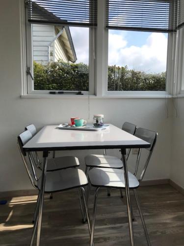 - une table et des chaises dans une chambre avec deux fenêtres dans l'établissement Vakantiehuisje in Ouddorp dichtbij het strand, à Ouddorp