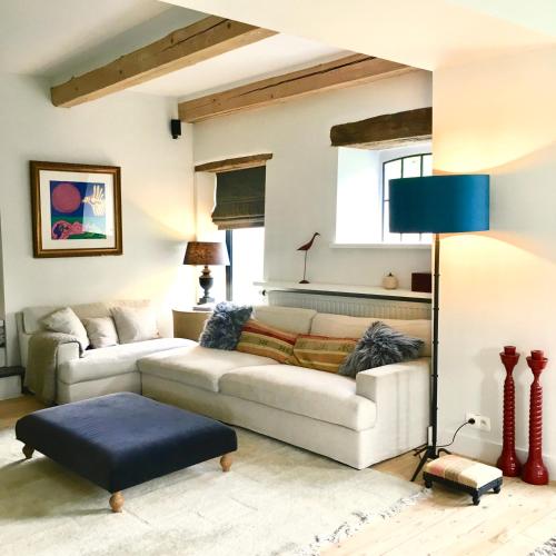 a living room with a white couch and a blue lamp at La Gotale - Maison d' Amis in Manhay