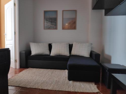 a living room with a black couch and a rug at Casa do Mar in Figueira da Foz
