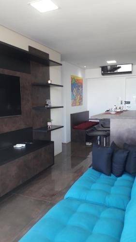 uma sala de estar com um sofá azul e uma mesa em Maravilhoso Apto Vista Mar Jacuzzi Wi Fi Pé Areia em Santos