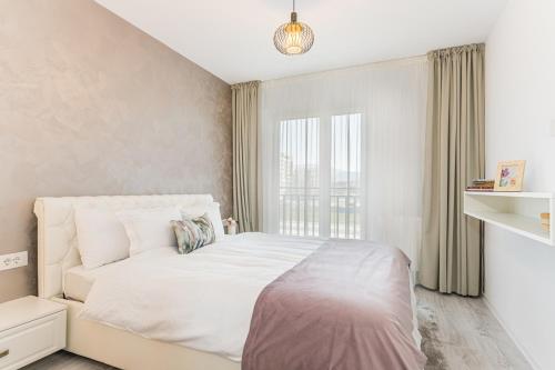 een slaapkamer met een wit bed en een raam bij RentForComfort Apartment Ella 2 in Braşov