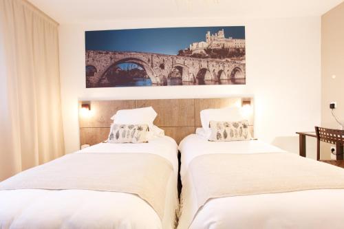 two beds in a room with a painting on the wall at Sure Hotel by Best Western Beziers Le Monestie in Béziers