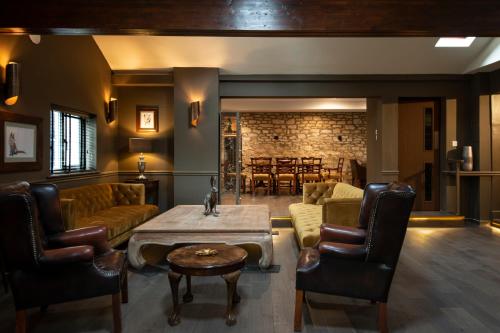 een woonkamer met een bank en een tafel en stoelen bij Pettifers Freehouse Hotel in Crudwell
