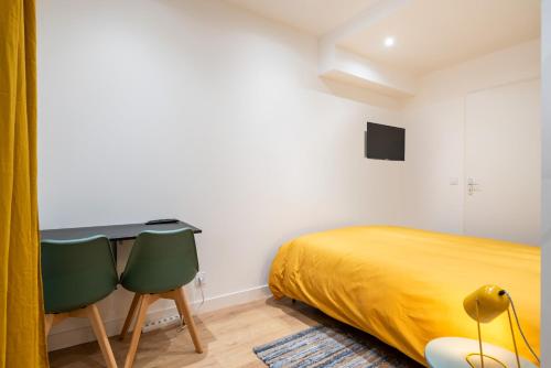 a bedroom with a bed and two chairs at Le Cocon De Paris in Lyon