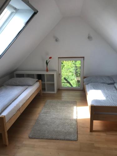Un dormitorio abuhardillado con dos camas y una ventana. en Siposréti Apartmanház, en Szentgyörgyvár