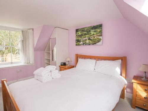 a bedroom with a large white bed and a window at Verdi in Pitlochry