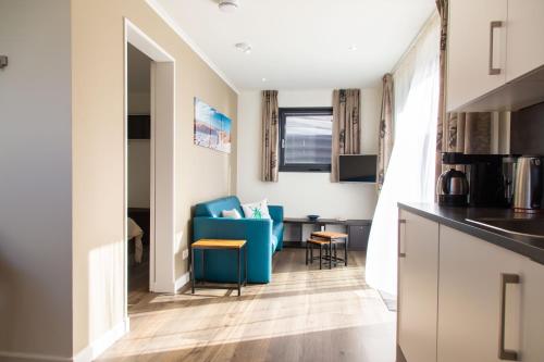 a kitchen and living room with a blue chair and a desk at Vrijstaande vakantiewoning Petite Renard in Zoutelande