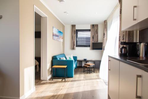 een keuken en een woonkamer met een blauwe stoel en een bureau bij Vrijstaande vakantiewoning Petite Renard in Zoutelande