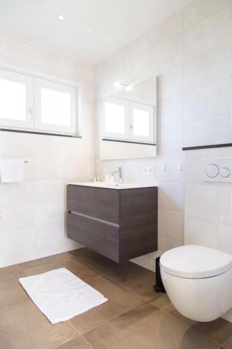 a white bathroom with a toilet and a sink at Luxe kamer Chambre Renard met eigen terras in Zoutelande
