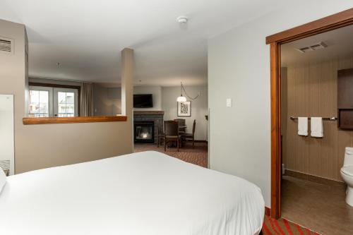 a bedroom with a white bed and a bathroom at La Tour des Voyageurs II in Mont-Tremblant