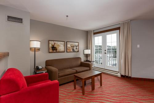 a living room with a couch and a red chair at La Tour des Voyageurs II in Mont-Tremblant